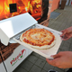 A customer in Bavaria reaches for a Pizza Margherita ejected from a vending machine after about three minutes of baking time.